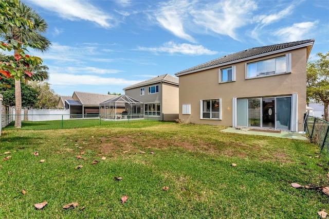 rear view of house with a lawn, stucco siding, a lanai, and a fenced backyard