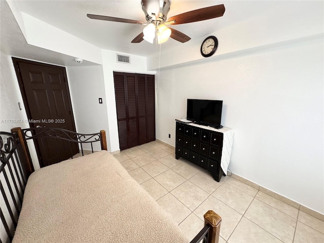 bedroom featuring light tile patterned floors, ceiling fan, visible vents, and a closet