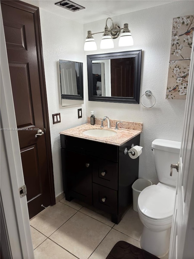 bathroom featuring visible vents, a textured wall, toilet, tile patterned flooring, and vanity