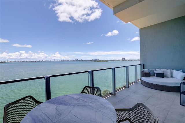 balcony featuring a water view, outdoor dining area, and outdoor lounge area