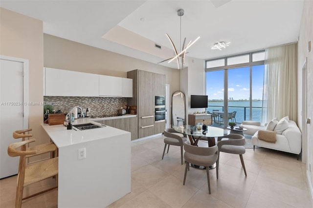 kitchen featuring light countertops, decorative backsplash, expansive windows, a sink, and modern cabinets