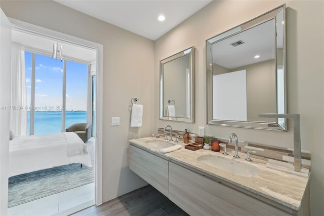 full bath featuring wood finished floors, visible vents, a sink, and double vanity