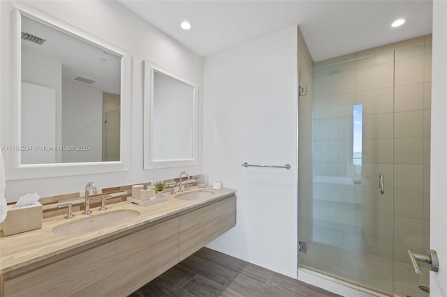 full bath featuring visible vents, a sink, a shower stall, and double vanity