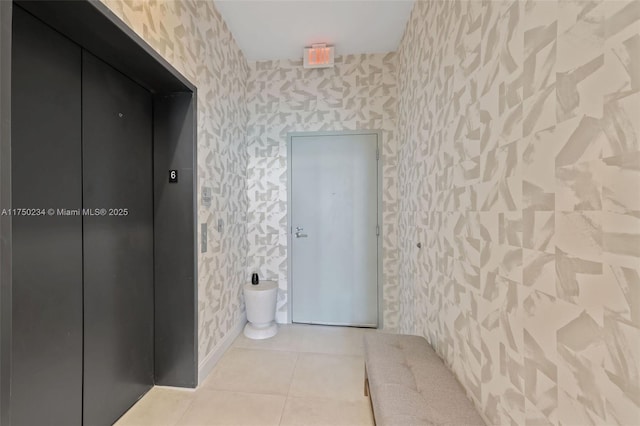 bathroom featuring tile patterned floors, elevator, baseboards, and wallpapered walls