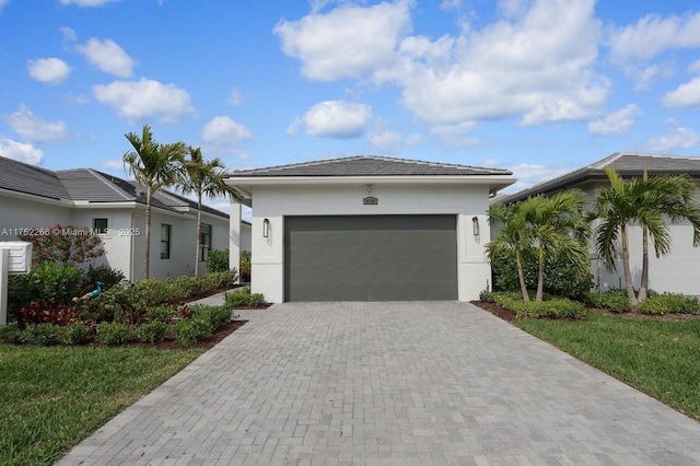 view of front facade featuring a garage, decorative driveway, and stucco siding