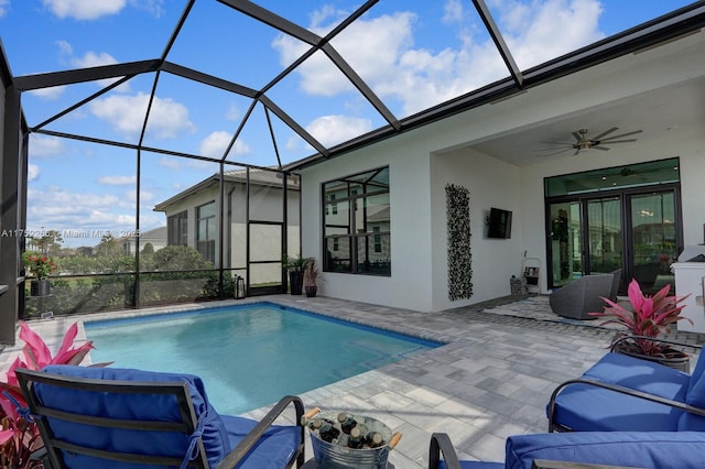 pool with glass enclosure, a patio, and ceiling fan