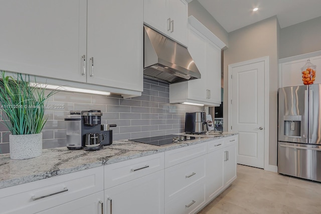 kitchen featuring light stone counters, black electric stovetop, under cabinet range hood, white cabinetry, and stainless steel refrigerator with ice dispenser