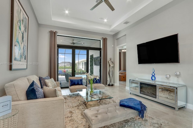 living area featuring baseboards, visible vents, a ceiling fan, a tray ceiling, and recessed lighting