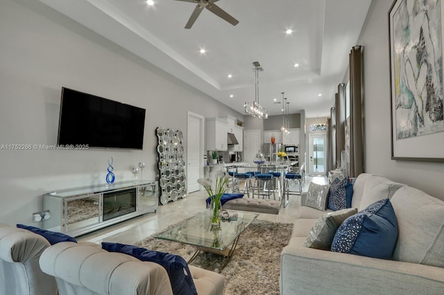 living room featuring ceiling fan, a tray ceiling, and recessed lighting