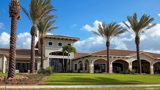 view of front of house featuring a tiled roof, a front lawn, and stucco siding