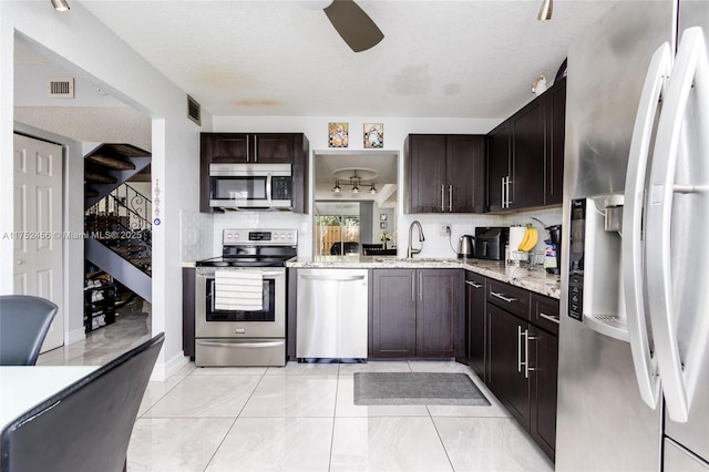 kitchen featuring a sink, visible vents, dark brown cabinets, appliances with stainless steel finishes, and light stone countertops