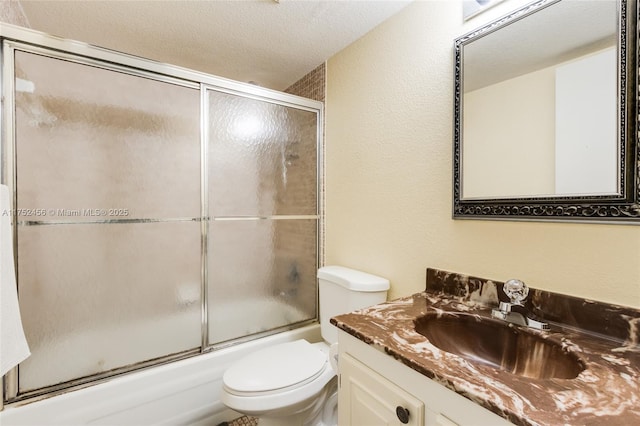 bathroom featuring enclosed tub / shower combo, vanity, toilet, and a textured ceiling