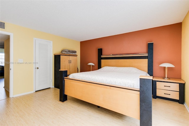 bedroom featuring light wood-style floors, visible vents, and baseboards