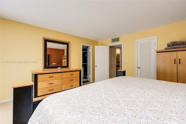 bedroom with a textured ceiling, visible vents, and baseboards