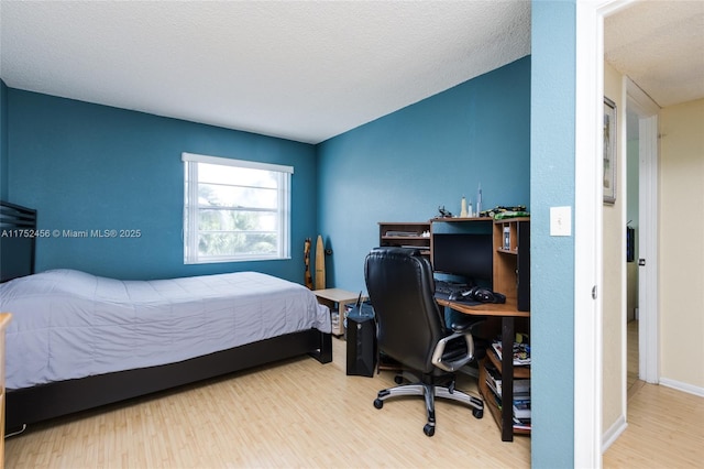 bedroom featuring a textured ceiling, wood finished floors, and baseboards