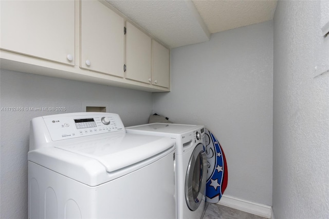 laundry area featuring cabinet space, baseboards, a textured wall, a textured ceiling, and washer and dryer