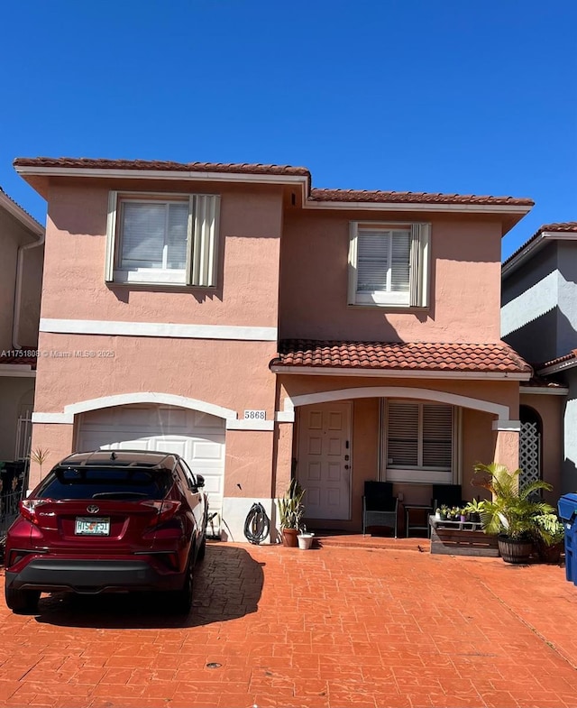 view of front of property featuring a tile roof, an attached garage, and stucco siding