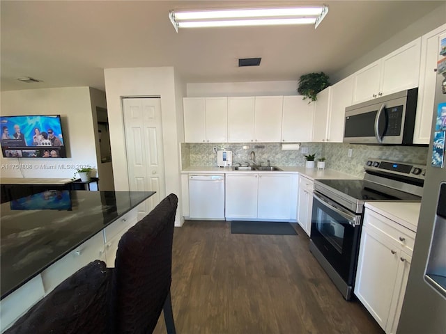 kitchen with stainless steel appliances, a sink, white cabinetry, and decorative backsplash