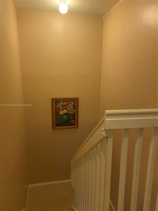 stairway with a textured ceiling and baseboards