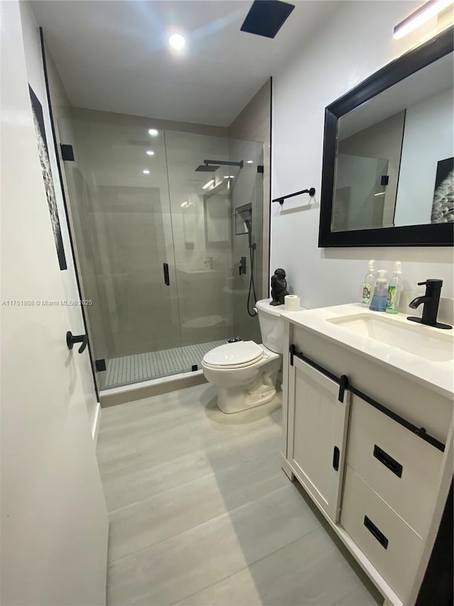 full bath with a stall shower, vanity, and toilet