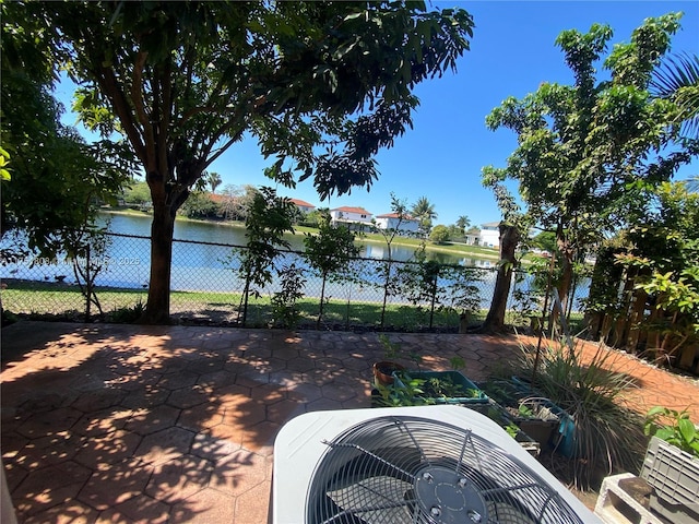 view of yard featuring a water view, fence, central AC, and a patio