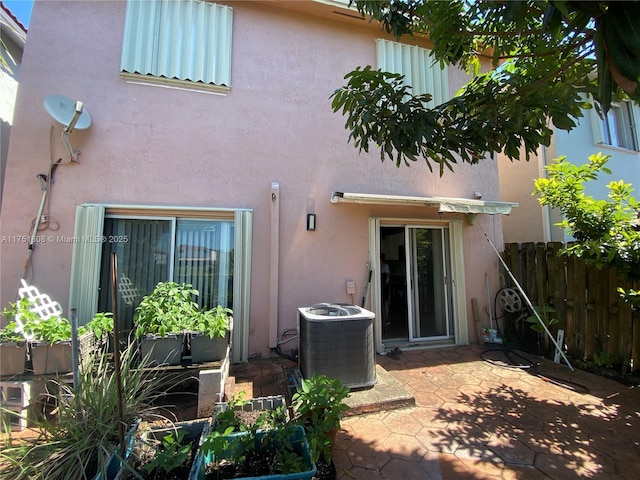 rear view of property featuring central AC, fence, and stucco siding