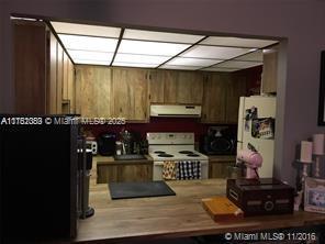 kitchen with white appliances, brown cabinets, and under cabinet range hood