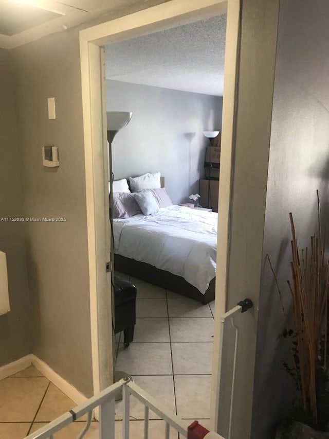 tiled bedroom featuring a textured ceiling and baseboards