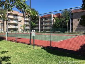 view of tennis court with a yard and fence