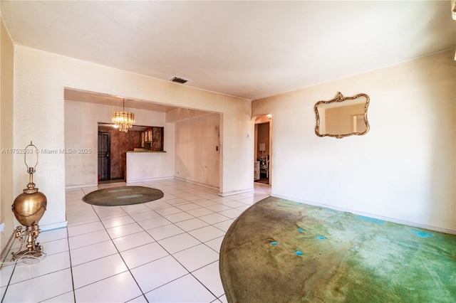 empty room featuring light carpet, light tile patterned flooring, baseboards, and a notable chandelier