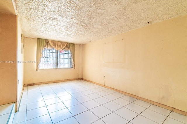 empty room with light tile patterned floors and a textured ceiling