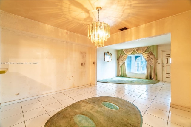 tiled spare room featuring visible vents and a chandelier