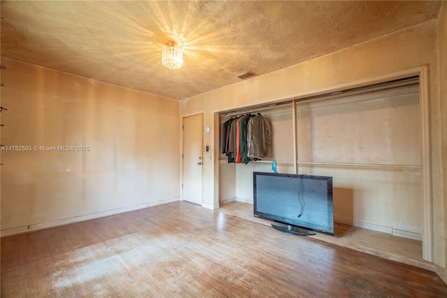 unfurnished bedroom featuring a closet, baseboards, and wood finished floors