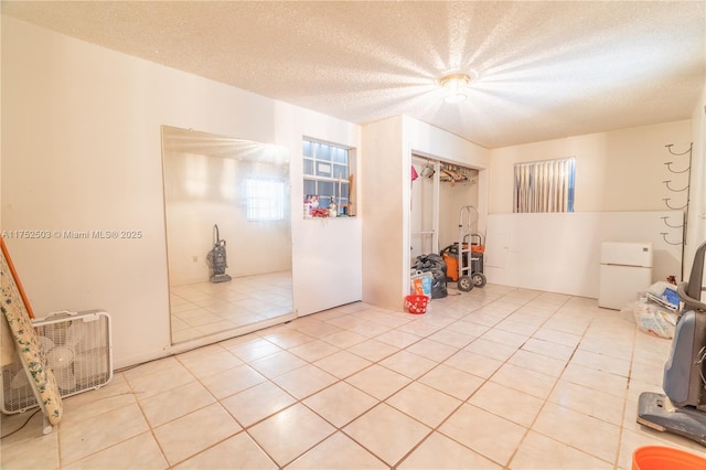 unfurnished room with a textured ceiling and light tile patterned floors