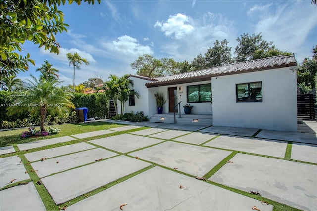 rear view of house with a patio area, a tiled roof, and stucco siding