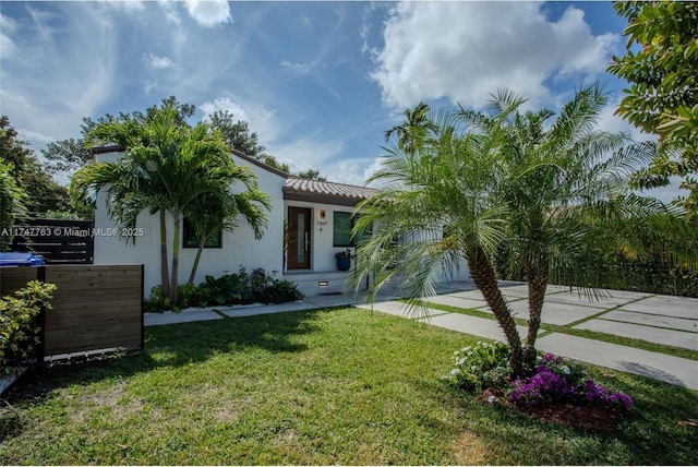 view of front of home featuring a garage, fence, driveway, stucco siding, and a front lawn