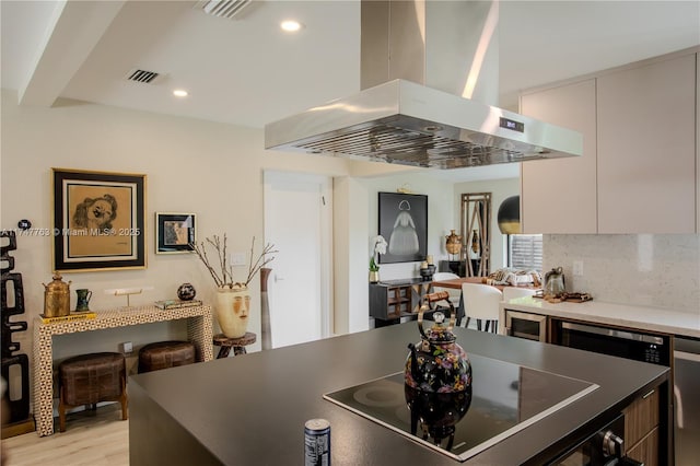 kitchen with black electric cooktop, island range hood, white cabinetry, backsplash, and modern cabinets