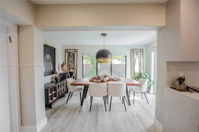 dining space featuring baseboards and light wood finished floors