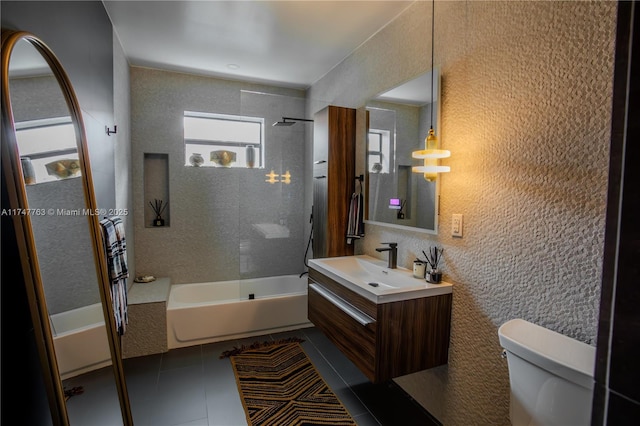 full bath with a textured wall, toilet, tile patterned floors, vanity, and shower / bathing tub combination