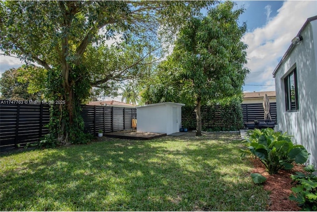 view of yard with an outbuilding, a fenced backyard, and a storage unit