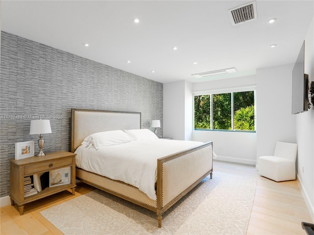 bedroom featuring recessed lighting, visible vents, light wood-style flooring, an accent wall, and wallpapered walls