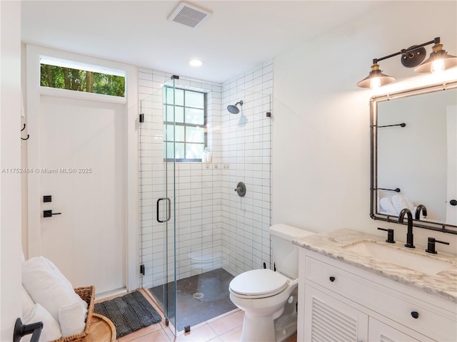 full bath featuring visible vents, toilet, vanity, a shower stall, and tile patterned flooring