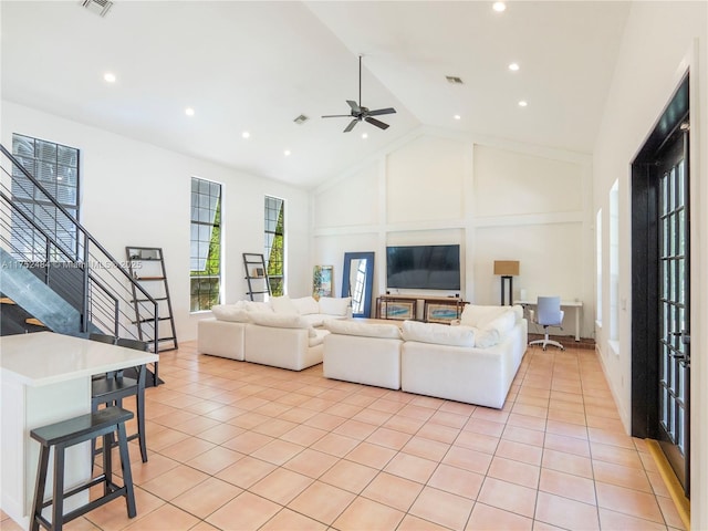 living room featuring light tile patterned floors, visible vents, stairs, and high vaulted ceiling