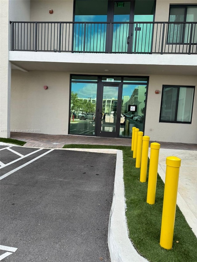 property entrance with uncovered parking, french doors, and stucco siding