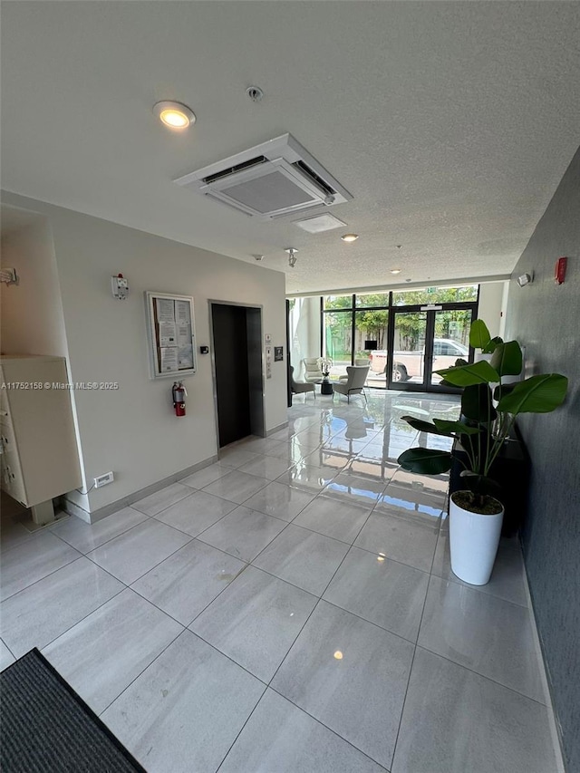 hall featuring expansive windows, elevator, light tile patterned flooring, a textured ceiling, and baseboards