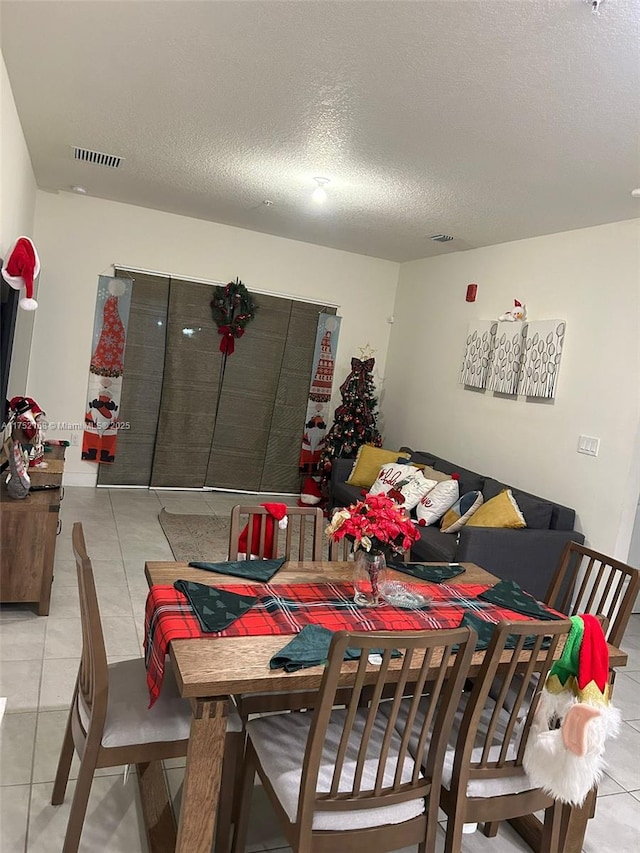 dining space with light tile patterned floors, a textured ceiling, and visible vents