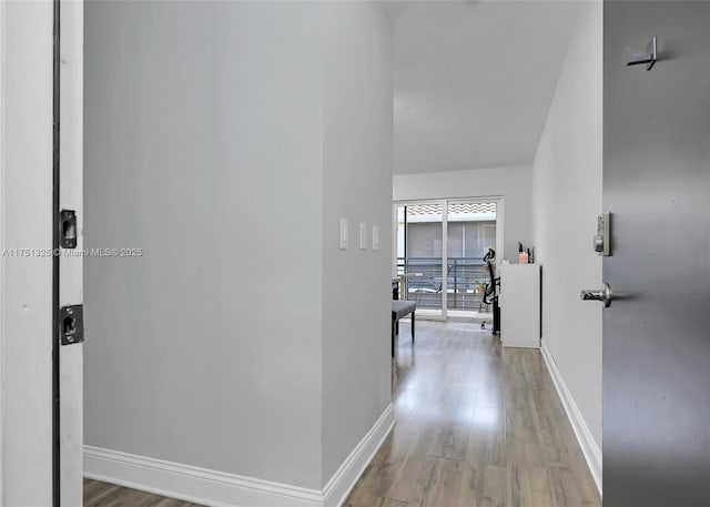 corridor with baseboards and wood finished floors