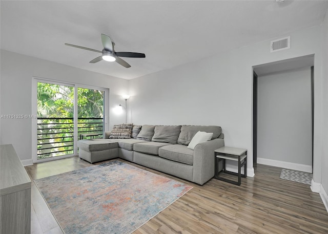 living room featuring baseboards, visible vents, ceiling fan, and wood finished floors