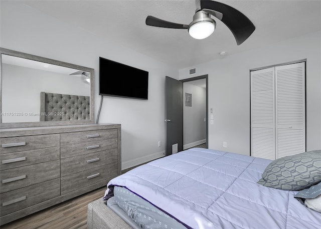 bedroom with a closet, visible vents, ceiling fan, a textured ceiling, and wood finished floors