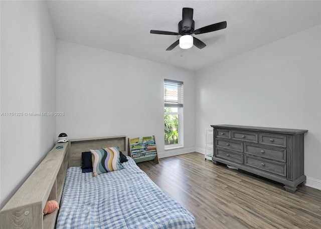 bedroom with a ceiling fan, a textured ceiling, baseboards, and wood finished floors